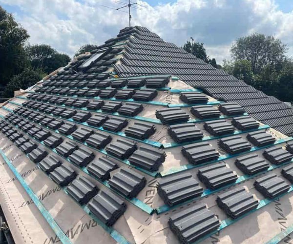 This is a photo of a new hip roof being installed. New felt, battens, and grey tiles have been installed, also a new velux window. Works carried out by DHT Roofing Cudworth