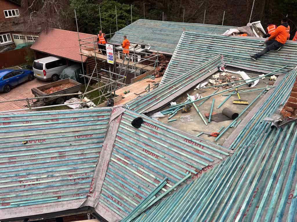 This is a photo of a large re-roof being carried out by DHT Roofing Cudworth, there are multiple sections of pitched roofs adjoining to a central flat roof